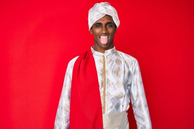 Sherwani sari giysisi giyen yakışıklı Hintli adam komik bir ifadeyle dilini dışarı çıkarıyor. duygu kavramı. 