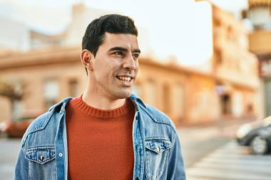 Genç İspanyol adam gülümseyerek şehirde mutlu mesut dikiliyor..