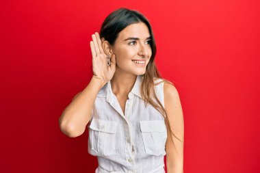 Günlük kıyafetler giyen, ağzı kulaklarında gülümseyen dedikoduları ve dedikoduları dinleyen genç İspanyol kadın. Sağırlık kavramı. 