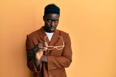 Zarif kıyafetler giyen, gözlüklü, kuşkucu ve gergin yakışıklı bir zenci, sorun yüzünden suratını asıyor. negatif kişi. 