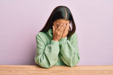 Güzel İspanyol kadın, gündelik giysiler giyip masaya oturmuş ağlarken suratını ellerle kapatıyor. depresyon kavramı. 
