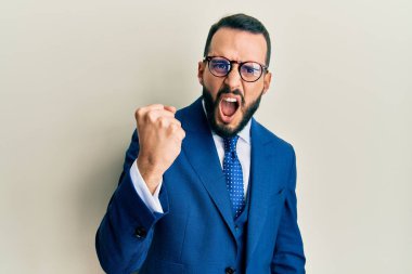 Sakallı, takım elbiseli, kravatlı kızgın ve kızgın bir genç öfkeyle bağırırken yumruğunu kaldırıyor. öfke ve agresif konsept. 