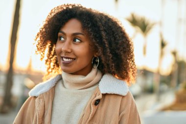 Genç Afrikalı Amerikalı kadın gülümseyerek şehirde mutlu mesut duruyor..