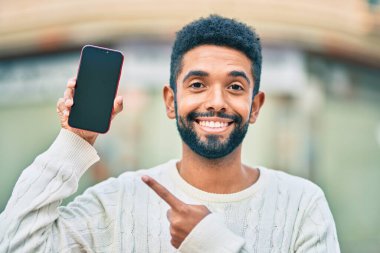 Genç Afrikalı Amerikalı adam gülümsüyor. Şehre akıllı telefon gösterdiği için mutlu..