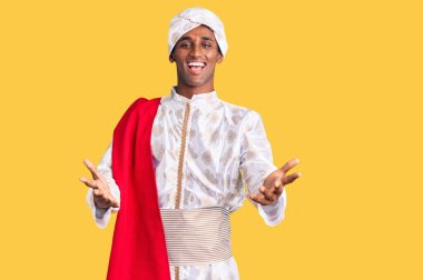 Gelenek giyinmiş Afrikalı yakışıklı bir adam Sherwani sari giysileri giyiyor. Gülümsüyor, yardım eli uzatıyor ve kabul ediyor.. 