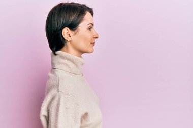 Kısa saçlı, kısa saçlı, kış süveteri giyen, rahat bir görünüm takınan, kendine güvenen gülümseyen genç esmer kadın.. 