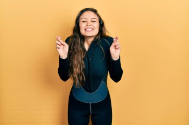 Genç İspanyol kız neoprene üniforması giyiyor. Umut ve gözlerin kapalı bir şekilde gülümseyerek işaret ediyor. Şans ve batıl inançlar. 