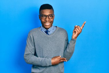 İş stili ve gözlük takan genç Afrikalı Amerikalı adam mutlu bir şekilde gülümsüyor. 