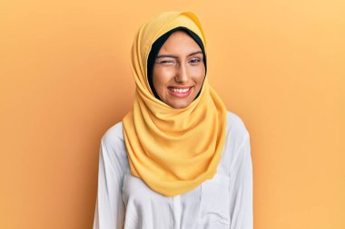 Genç esmer Arap kadın geleneksel başörtüsü takıyor kameraya seksi bir ifadeyle bakıyor, neşeli ve mutlu bir yüzle.. 