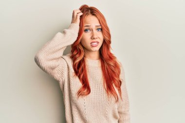 Kış süveteri giyen genç, güzel, kızıl saçlı bir kadın soru sorup kafasını karıştırıyor. Şüpheyle kararsız, kafa kafaya düşünerek. Düşünceli kavram. 