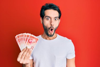 Genç İspanyol adam elinde 20 İsrail şekeri tutuyor. Banknotlar korkmuş ve ağzı açık kalmış, şaşırmış, inançsız bir yüz. 