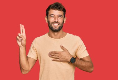 Sakallı, sıradan bir tişört giyen, eli göğsünde, parmakları havada küfreden, sadakat yemini eden yakışıklı bir genç. 