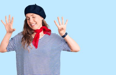 Fransız beresi ve çizgili tişört giyen genç ve güzel sarışın kadın dokuz numaralı parmaklarını gösterip gösterirken kendinden emin ve mutlu bir şekilde gülümsüyor.. 