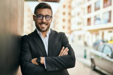 Kollarını kavuşturmuş genç İspanyol işadamı şehirde mutlu bir şekilde gülümsüyor..