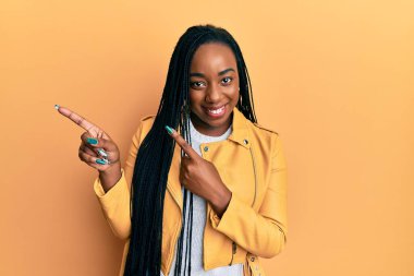 Sıradan bir ceket giyen, gülümseyen ve kameraya bakan Afro-Amerikalı genç bir kadın.. 