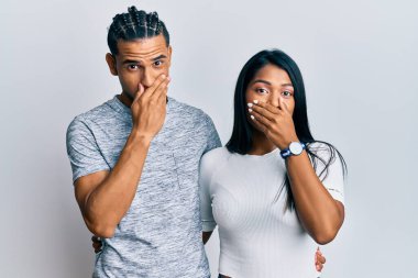 Gündelik giysiler giyen genç latin çift yanlışlıkla ağızlarını elleriyle kapatırken şok oldu. gizli kavram. 