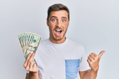 Elinde 20 dolarlık banknot tutan yakışıklı beyaz adam başparmağını yana kaldırmış, ağzı açık gülümsüyor. 