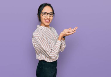Gündelik kıyafetler ve gözlük takan genç İspanyol kız avuç içlerini açıp fotokopi alanını gösteriyor, gülümseyerek mutlu bir şekilde gülümsüyor. 