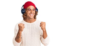 Müzik dinleyen genç İspanyol adam kulaklık takıyor. Başarı için heyecanlı kollar havada ve gözleri kapalı zaferi kutlarken gülümsüyor. Kazanan konsept. 