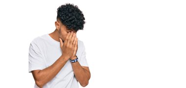 Genç Arap adam, ağlarken suratını ellerle kapatan sıradan beyaz tişört giyiyor. depresyon kavramı. 