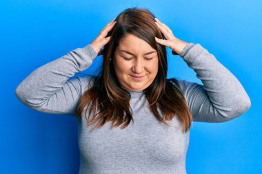 Güzel esmer ve kilolu bir kadın stres yüzünden elleri başının üstünde gündelik kıyafetler giyiyor. migren ağrısı. 