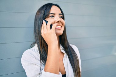 Genç İspanyol kız gülümsüyor. Şehirdeki akıllı telefondan konuşuyor..