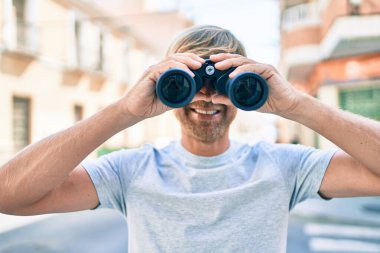 Şehrin caddesinde dürbünle gülümseyen genç İrlandalı adam..