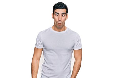 Beyaz bir tişört giyen yakışıklı İspanyol dudaklı balık suratı yapan çılgın ve komik bir jest. Komik ifade. 