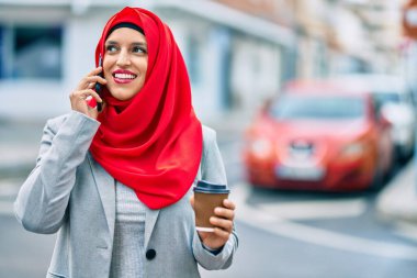 Genç Arap iş kadını akıllı telefondan konuşuyor ve şehirde kahve içiyor..