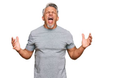 Orta yaşlı, gri saçlı, sıradan kıyafetler giyen çılgın ve kızgın bir adam agresif bir ifadeyle bağırıyor ve kollarını kaldırıyor. hüsran kavramı. 