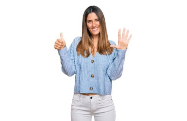 Gündelik kıyafetler giyen genç bir kadın altı numarayı gösterip işaret ederken kendinden emin ve mutlu bir şekilde gülümsüyor.. 