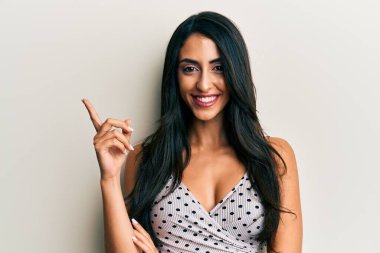 Güzel İspanyol kadın gündelik kıyafetler giyip gülümsüyor mutlu bir şekilde elini ve parmağını yana uzatıyordu. 