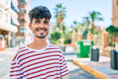 Genç İspanyol adam gülümsüyor Mutlu bir şekilde yürüyor şehrin caddesinde.