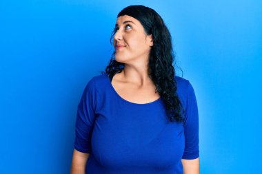 Artı mavi gömlekli esmer kadın gülümseyerek yan tarafa bakıyor ve düşünüyor.. 
