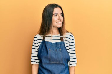 Berber önlüğü takan genç İspanyol kadın yüzünde gülümseme, doğal bir ifade ile yan yana bakıyor. Kendinden emin gülen. 