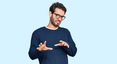 Gündelik kıyafetler ve gözlük takan genç İspanyol adam tiksindirici tepki verdiği için tiksinmiş ve korkmuş bir ifade takınıyordu. Eller havada. 