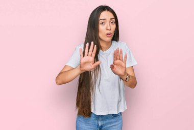 Latin kökenli genç bir kız günlük beyaz tişörtler giyer, avuç içlerini çeker, reddeder ve iğrenç bir ifadeyle reddeder. Dur ve yasakla. 