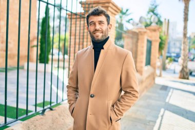 Zarif ceket giyen yakışıklı iş adamı dışarıda mutlu bir şekilde gülümsüyor.