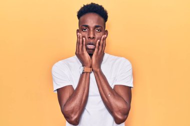 Genç Afro-Amerikan adam günlük kıyafetler giyiyor. Yorgun eller, yüzünü kapatıyor. Depresyon ve üzüntü yaşıyor. 