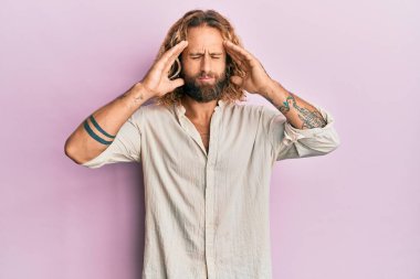 Sakallı, uzun saçlı, sıradan kıyafetler giyen, başı ağrıyan yakışıklı bir adam. migren ağrısı. 