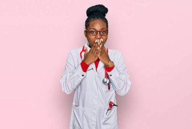 Genç Afrikalı Amerikalı kadın doktor üniforması ve steteskop giyip gülüyor ve utanıyor kıkırdıyor ağızları ellerle, dedikodularla ve skandallarla örtüyor. 