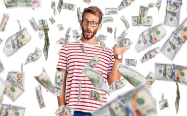 Sakallı, sıradan giyinen ve gözlüklü yakışıklı sarışın adam el parmağı yana dönük, ağzı açık, şaşkın bir ifade sergiliyor..