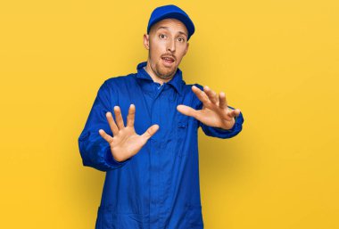 Sakallı, inşaatçı üniforması giyen, korku ifadesinden korkan ve dehşete düşmüş kel bir adam. El kol hareketi yapmayı kes, şok içinde bağır. panik konsepti. 