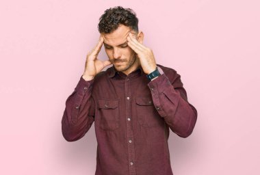 Latin asıllı genç bir adam elleri kafasında günlük kıyafetler giyiyor, stres yüzünden baş ağrısı çekiyor. migren ağrısı. 