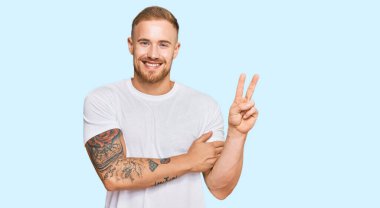 Sıradan kıyafetler giyen genç İrlandalı adam kameraya göz kırparak gülümsüyor zafer işareti yapıyor. İki numara.. 