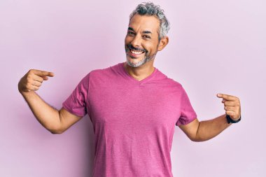 Orta yaşlı, gri saçlı, günlük kıyafetler giyen, kendine güvenen, gülümseyen, kendini gururlu ve mutlu gösteren bir adam.. 