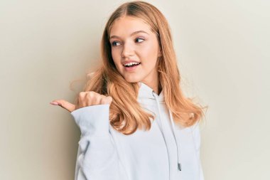 Güzelim beyaz kız, günlük eşofman üstüyle başparmağını kaldırıyor, ağzı açık gülümsüyor. 