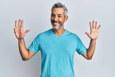 Orta yaşlı, gri saçlı, günlük kıyafetler giyen, dokuz numaralı parmaklarıyla işaret eden, kendinden emin ve mutlu bir adam.. 