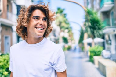 Genç, yakışıklı, gülümseyen bir İspanyol. Şehrin caddesinde mutlu bir şekilde yürüyor.