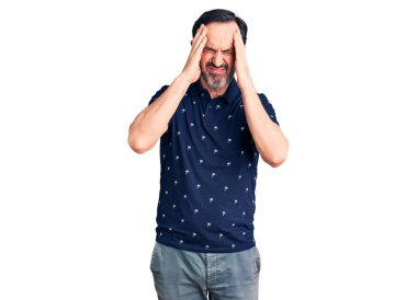 Orta yaşlı yakışıklı bir adam gündelik polo giyip baş ağrısı çekiyor. Acı ve migren yüzünden çaresiz ve stresli. Eller başının üstünde.. 